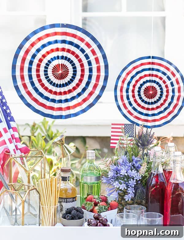 Stars Stripes and Spiked Slushies 2 A vibrant 4th of July boozy snow cone stand adorned with colorful syrups, assorted spirits, fresh berries, decorative paper fans, and festive flowers, set for a lively party.
