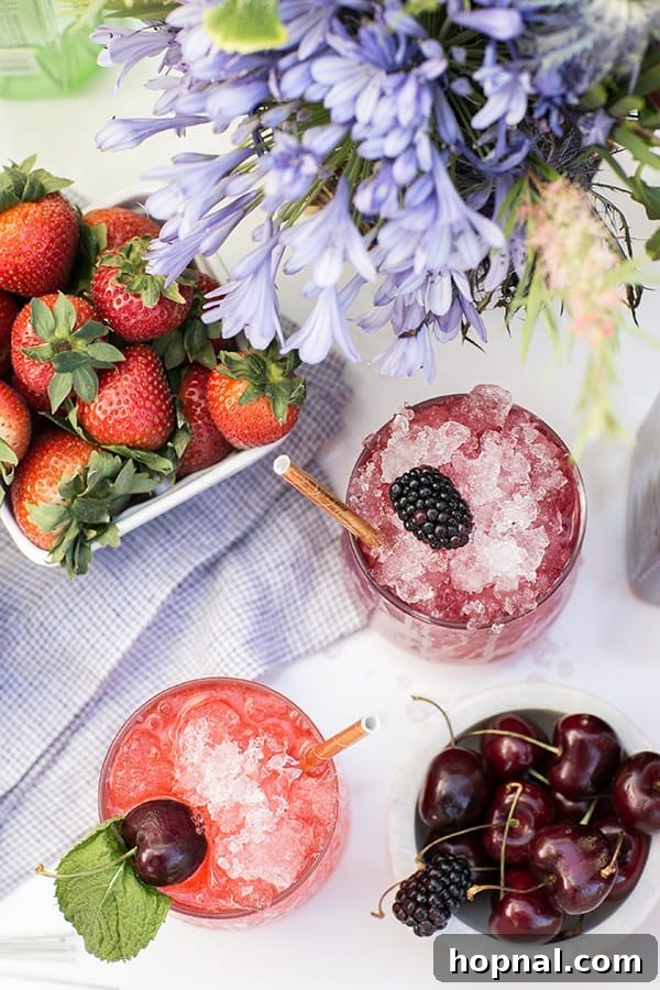 Stars Stripes and Spiked Slushies 4 Two exquisitely crafted boozy snow cones, adorned with fresh berries and aromatic mint leaves, presented alongside a bowl brimming with luscious cherries and ripe strawberries, embodying a luxurious summer indulgence.