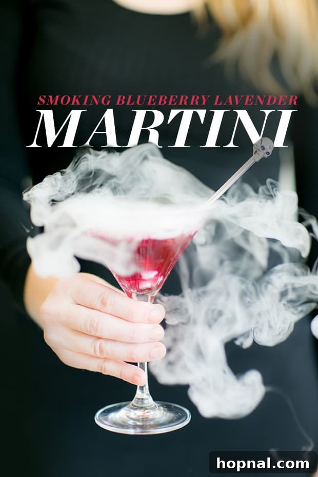 A smoking lavender blueberry martini in a elegant glass, perfect for Halloween.