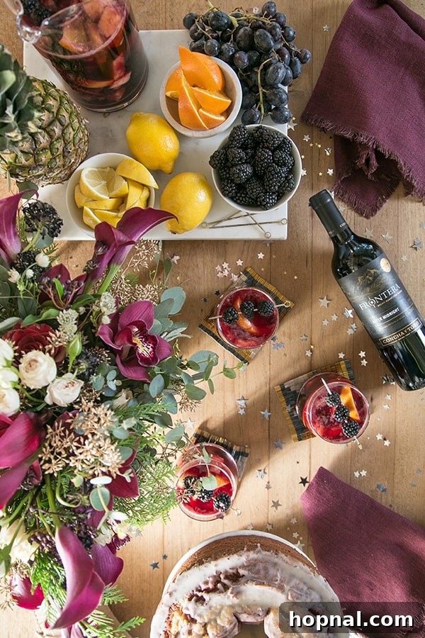 An overhead view of a vibrant DIY sangria bar setup with sliced oranges, lemons, pineapple, and blackberries, a bottle of red wine, and a glass of sangria ready to be customized.