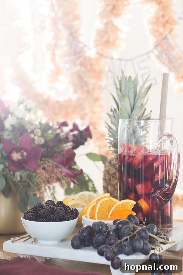 A marble tray filled with an assortment of fresh fruits like oranges, lemons, limes, and berries, next to a glass pitcher of sangria, showcasing elegant party presentation.