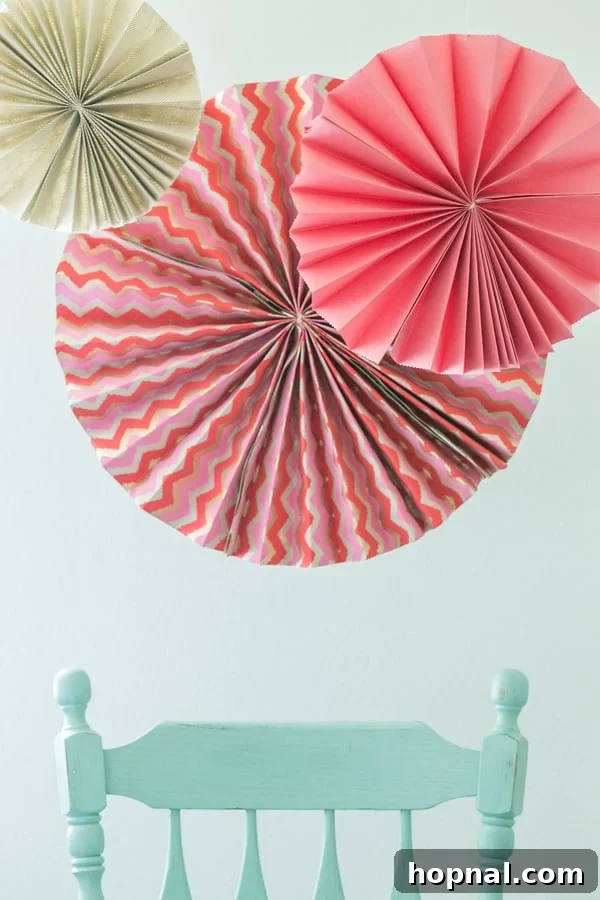 Elevate Your Decor With DIY Giant Party Fans 2 Beautiful DIY paper fans hanging above a chair, creating a festive backdrop