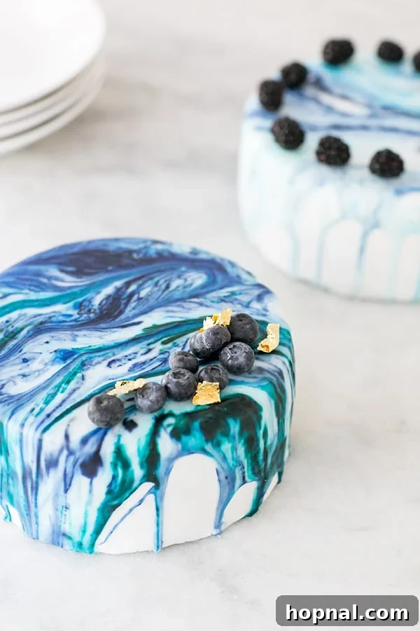 Two beautifully crafted marble drip cakes sitting on a kitchen counter, ready for decoration or display.