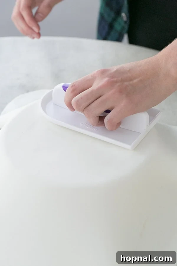 Detailed shot of fondant being rolled out thinly and evenly, demonstrating the process.