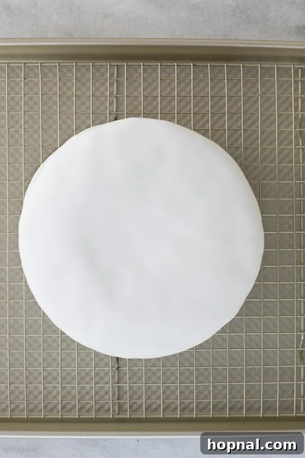 A single round cake perfectly encased in pristine white fondant, showcasing a smooth and even finish.