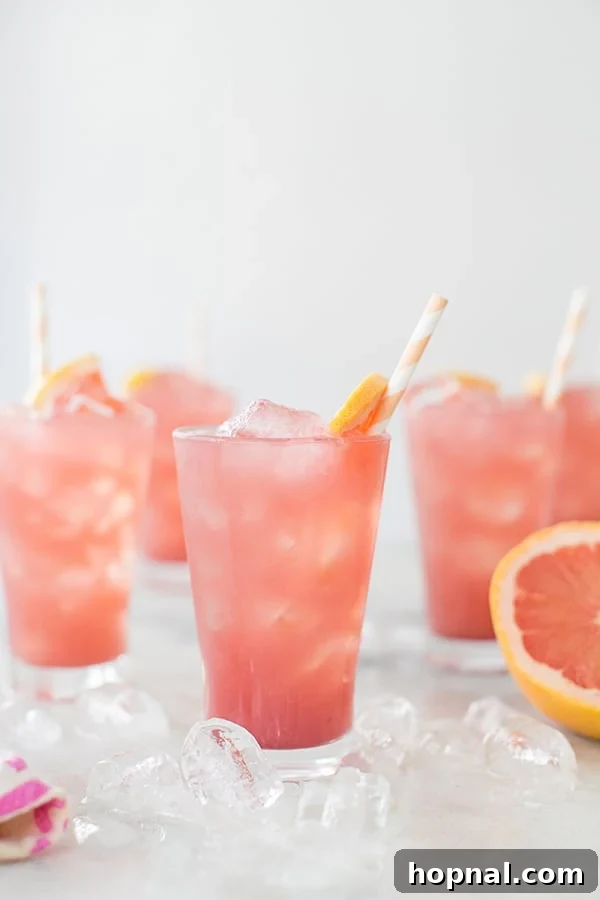 Side shot of a vibrant sparkling grapefruit cocktail garnished with a fresh grapefruit wedge, ready for a summer day.