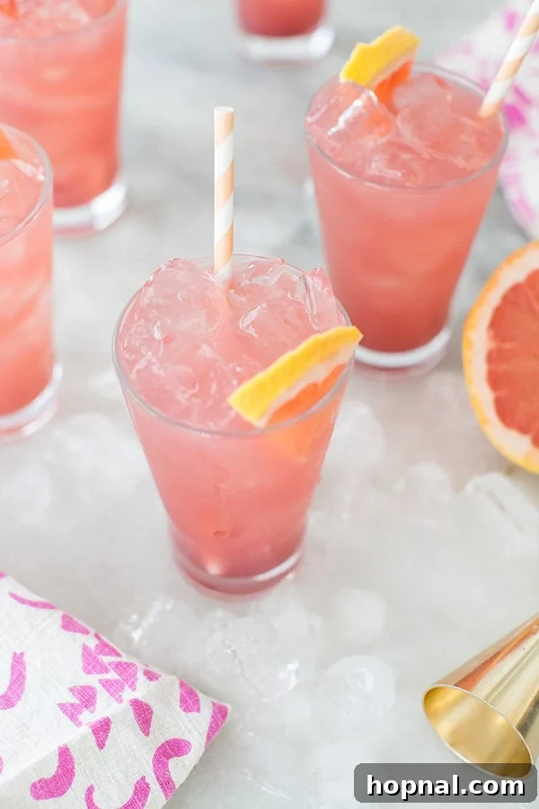 Close up of a sparkling pink grapefruit cocktail in an elegant glass, showing its refreshing bubbles and vibrant color.