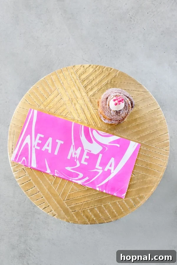 A delicious cruffin and a pink branded bag resting on a gold table, embodying the stylish vibe of Mr. Holmes Bakehouse.