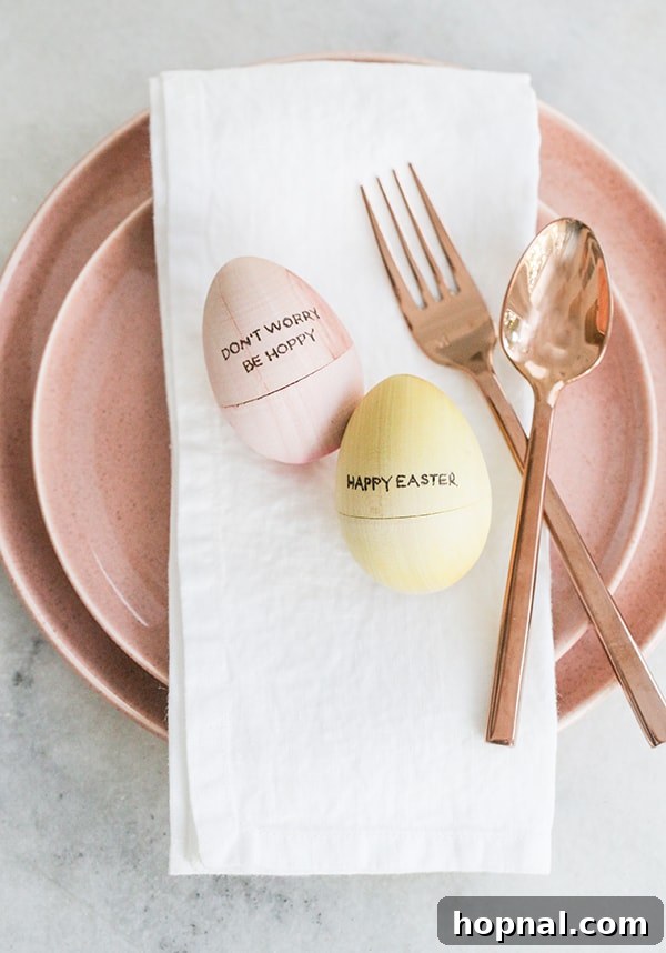Heirloom Pyrography Easter Eggs 7 A pink and yellow wooden egg with engraved letters, elegantly placed on a pink plate with copper flatware, ready for an Easter brunch.