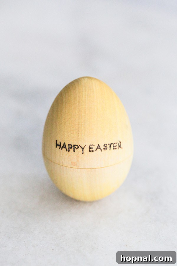 Heirloom Pyrography Easter Eggs 10 A charming yellow wooden egg, delicately engraved with the words 'Happy Easter'.