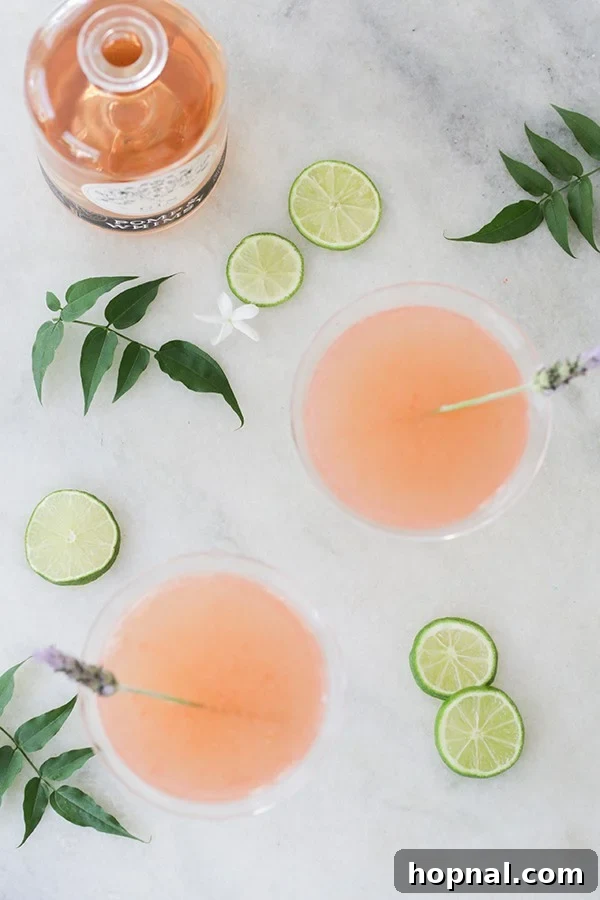 The Whippet's Whimsical Pageant 5 Floral cocktail using Pomp & Whimsy with lime wedges and flowers.
