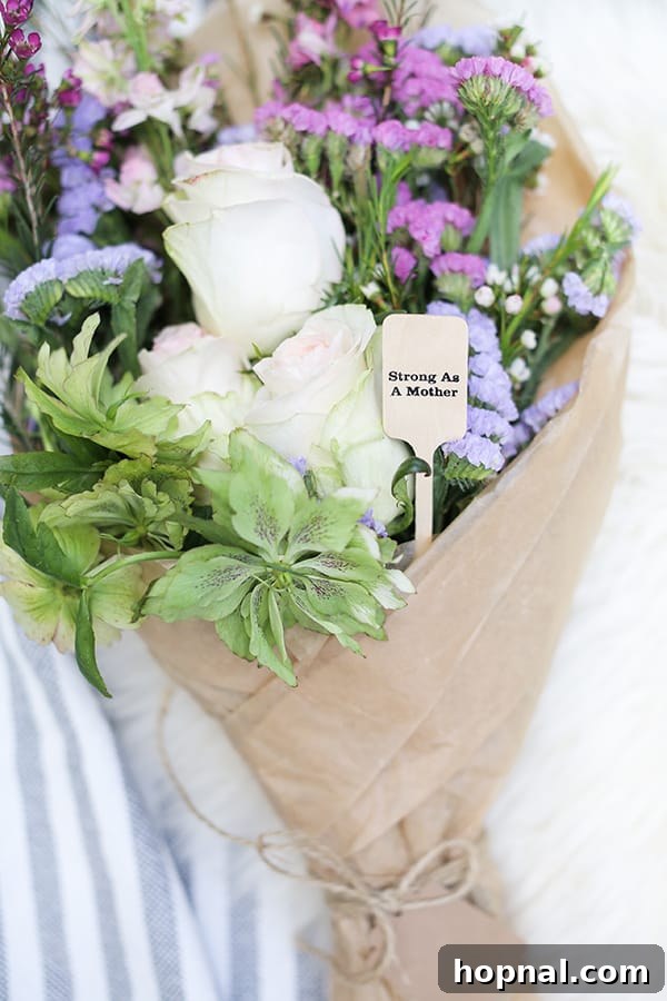 A charming bouquet of flowers accented with a wooden stir stick inscribed with 'strong as a mother,' symbolizing enduring strength and beauty.