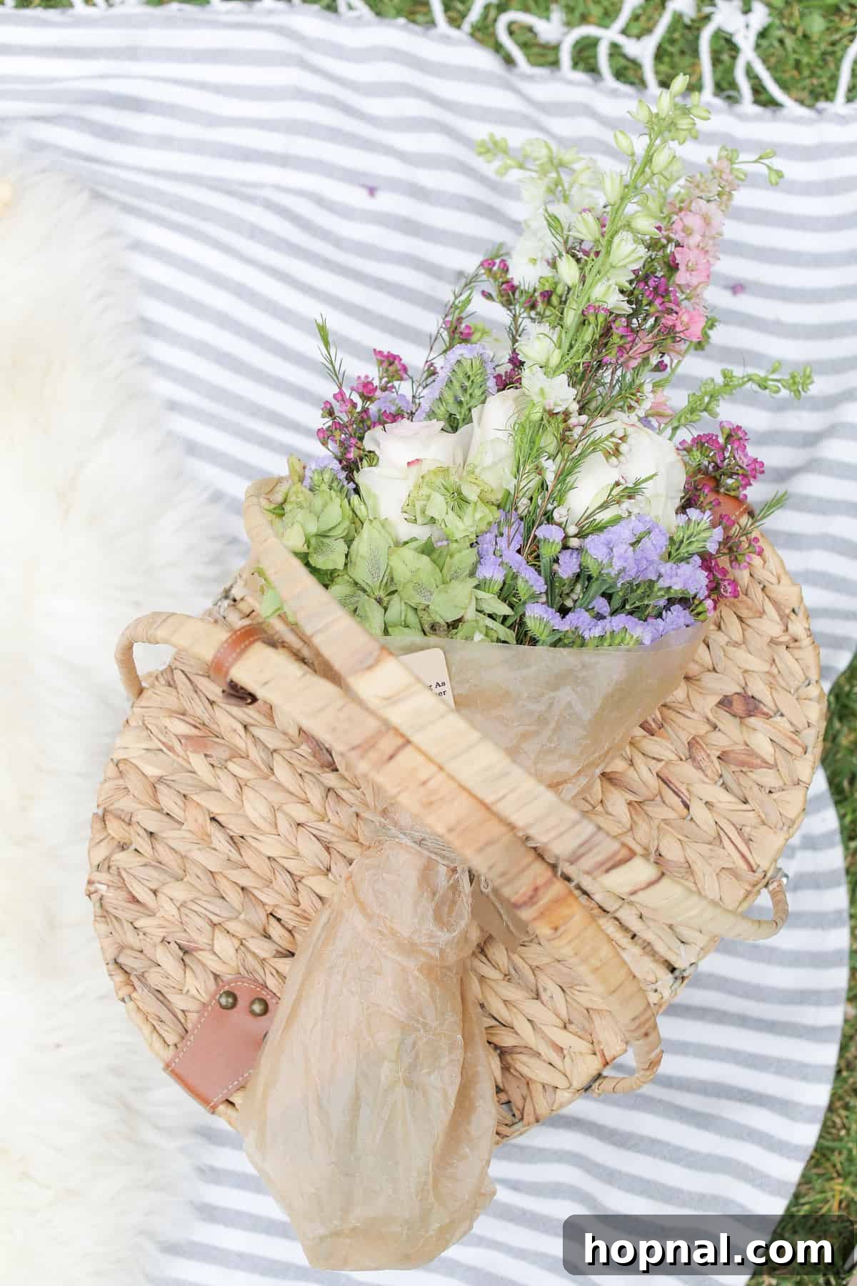 A classic wicker picnic basket elegantly set with a soft picnic blanket and a lovely bouquet of flowers, inviting a relaxing outdoor meal.