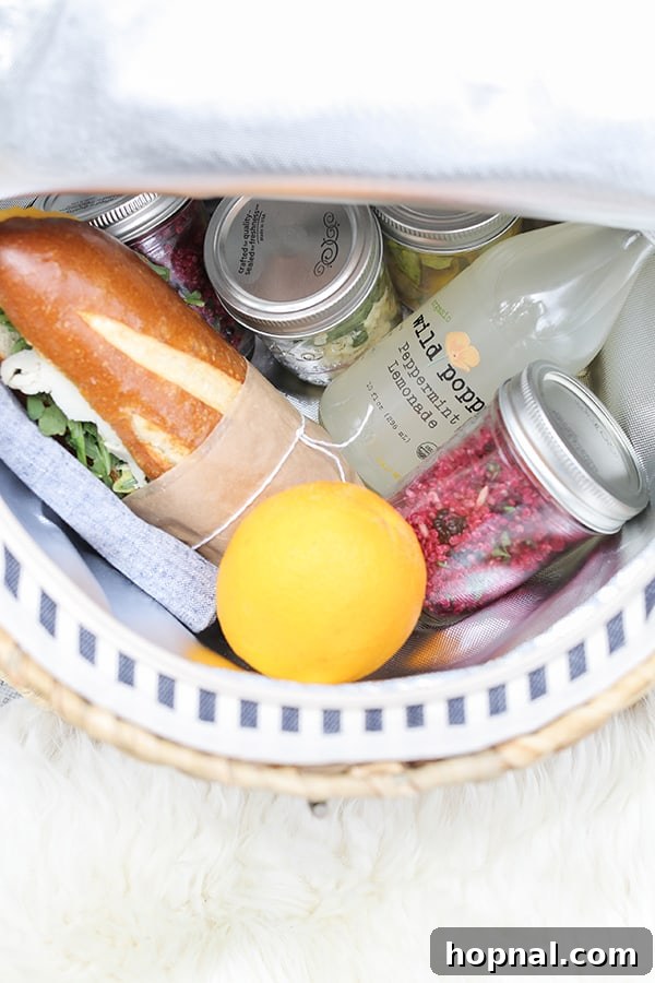 Assortment of vibrant picnic food, including sandwiches and drinks, neatly arranged inside a rustic picnic basket with floral accents.