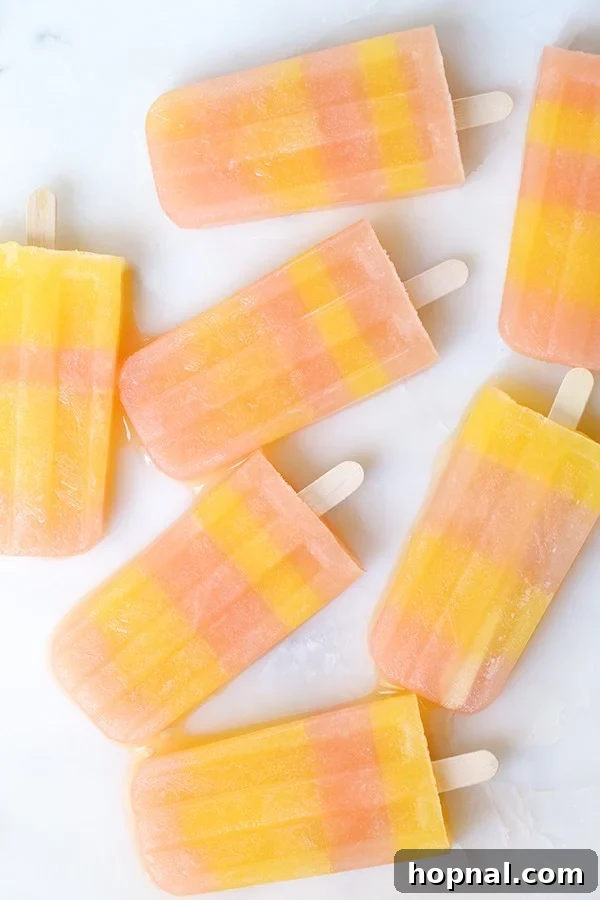 Boozy Greyhound Pops 6 Striped popsicles on a marble table, showcasing their elegant appearance.