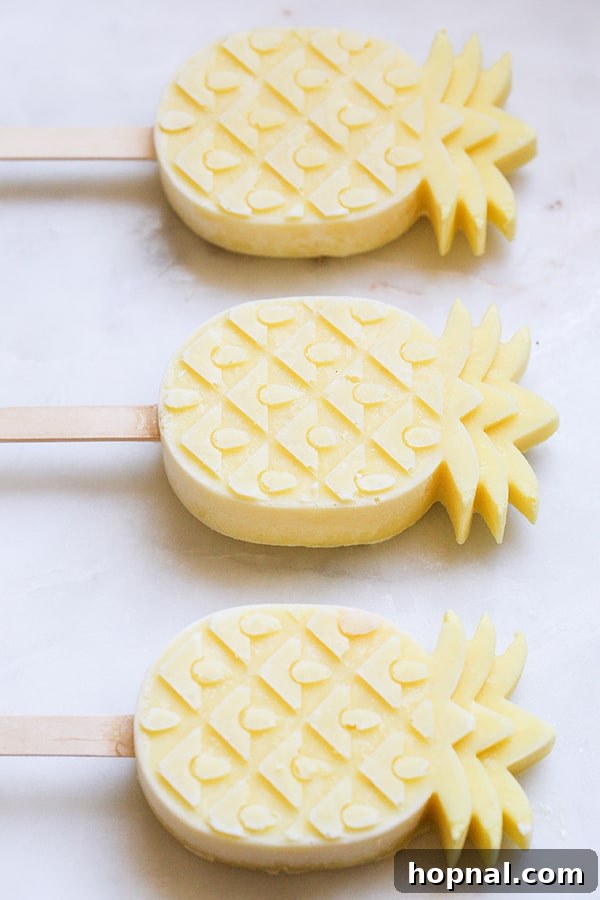 Top down shot of three pineapple-shaped popsicles arranged artfully on a surface