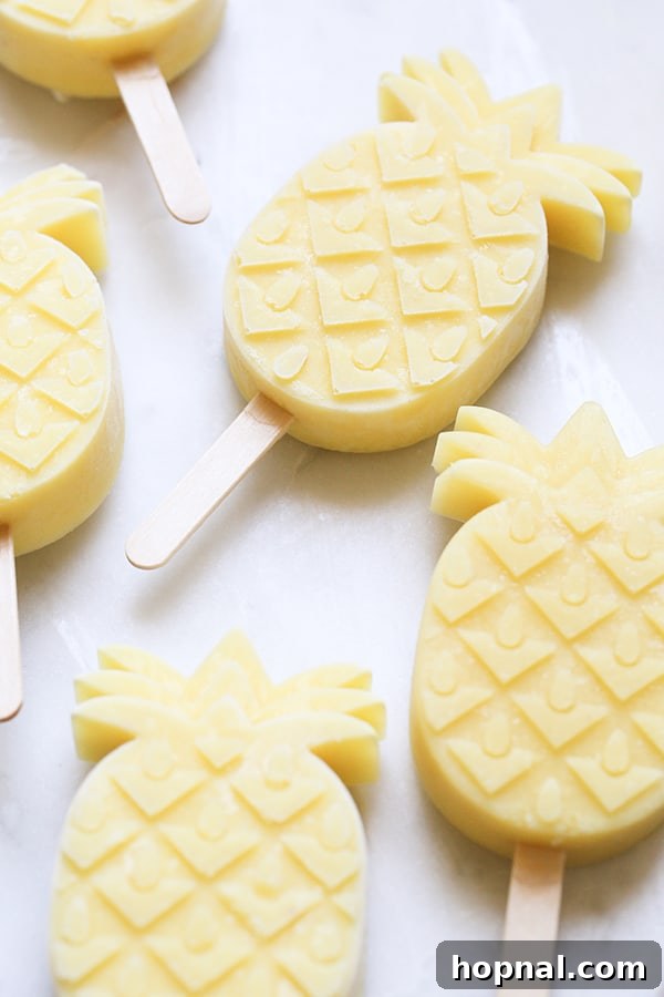 Several pineapple coconut rum popsicles arranged on a marble table, ready to be enjoyed