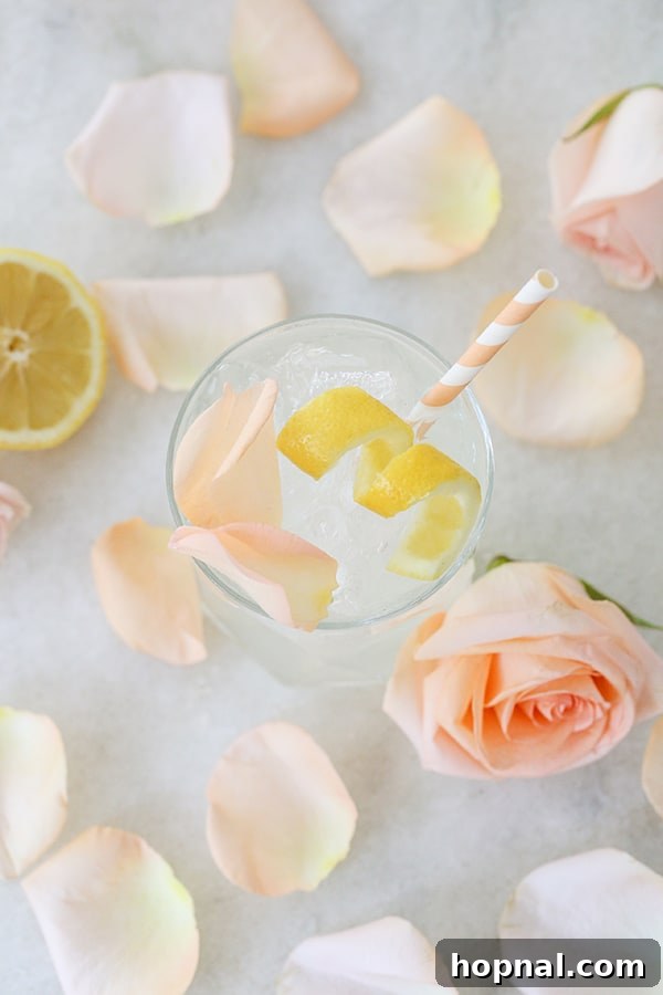 Petal Potion 3 Close-up of a Rose Water Cocktail served in a coupe glass, garnished with a lemon wedge and rose petals.