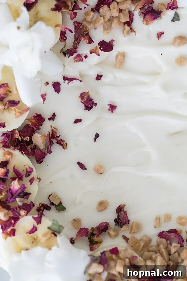 Super Moist Banana Cake Made with Oil 4 Luxurious cream cheese frosting adorned with delicate edible flowers and crunchy nuts, showcasing a decorative banana cake.