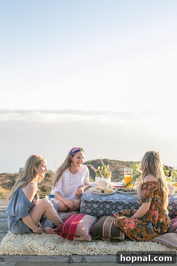 The Art of Airstream Entertaining in Malibu 11 A group of girls gathered around a table on a deck in Malibu, enjoying their glamping experience and conversation.