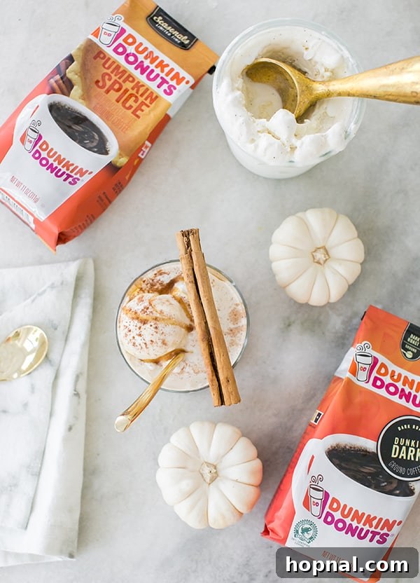 Autumn Spiced Affogato Dream 3 Overhead view of a prepared pumpkin spice affogato with ice cream, coffee, a cinnamon stick, and mini white pumpkins on a wooden surface.