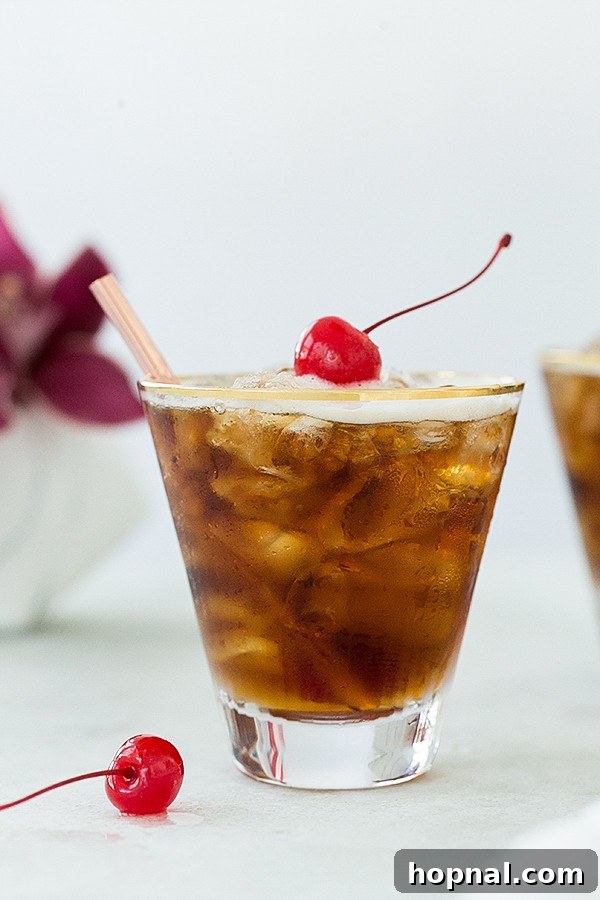 Close-up of a refreshing coffee tonic drink, adorned with a single red maraschino cherry.