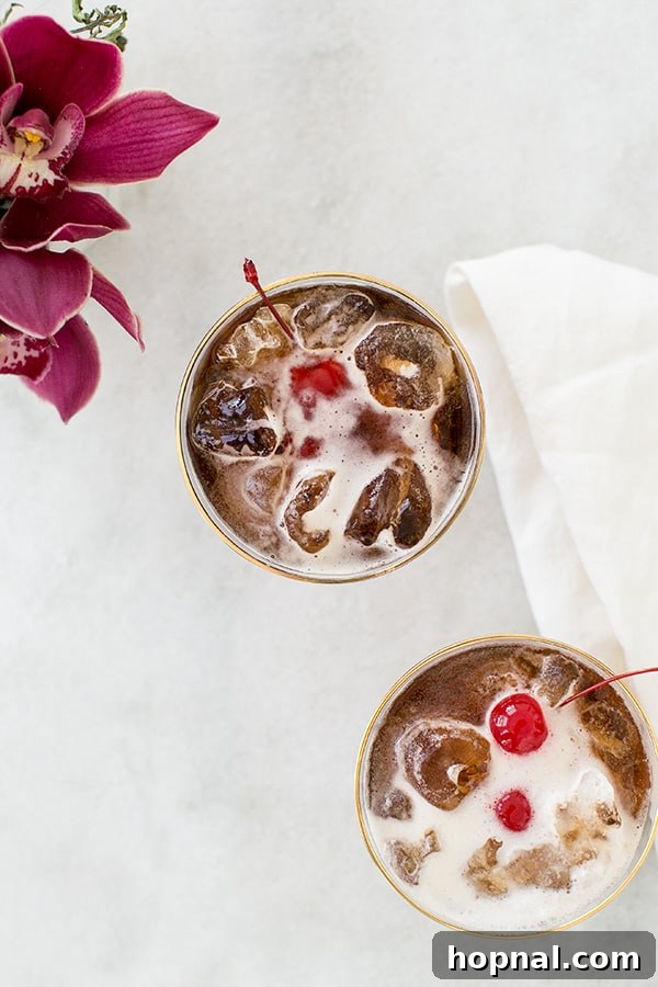 Ingredients for coffee tonic laid out: glass, ice, cold brew, tonic, and a jar of cherries.
