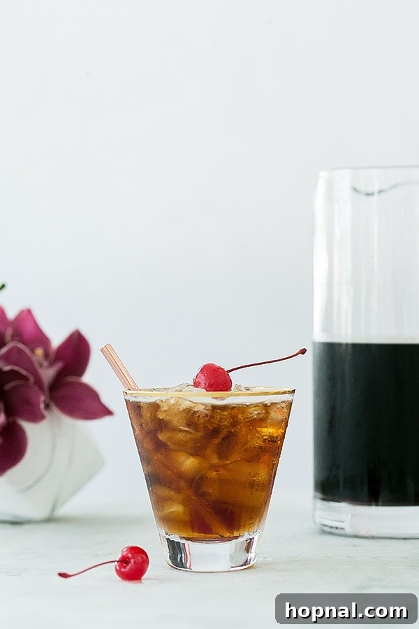Another view of a freshly made coffee tonic, topped with a red cherry.