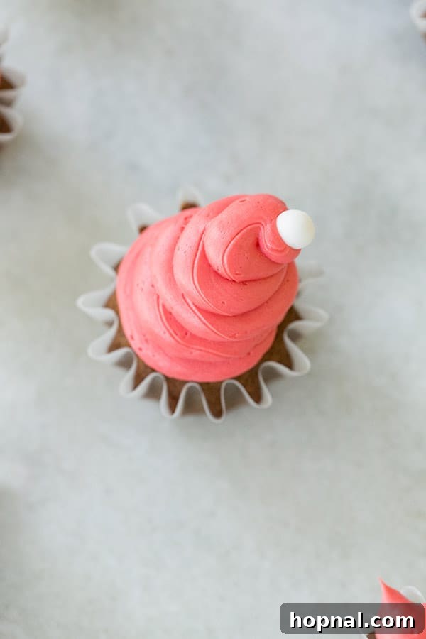 A single gingerbread cupcake beautifully frosted with vibrant red buttercream, ready for its white trim.