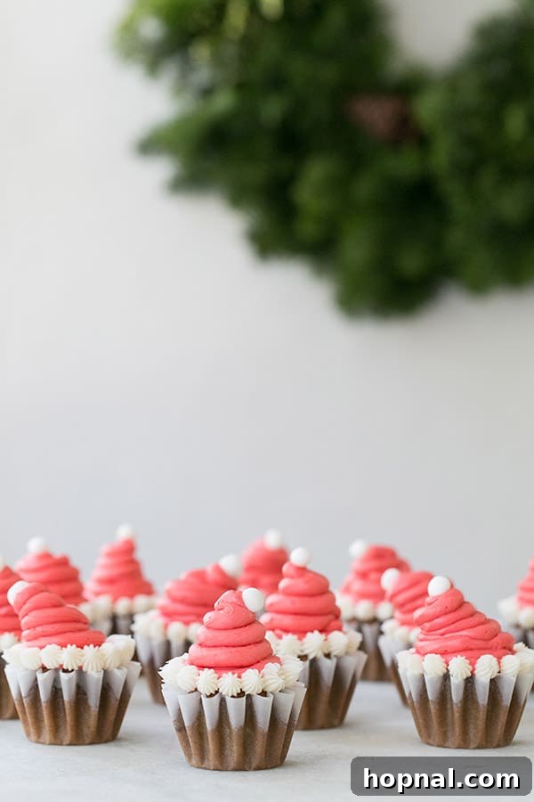 A delightful array of gingerbread cupcakes, each adorned with miniature Santa hats.