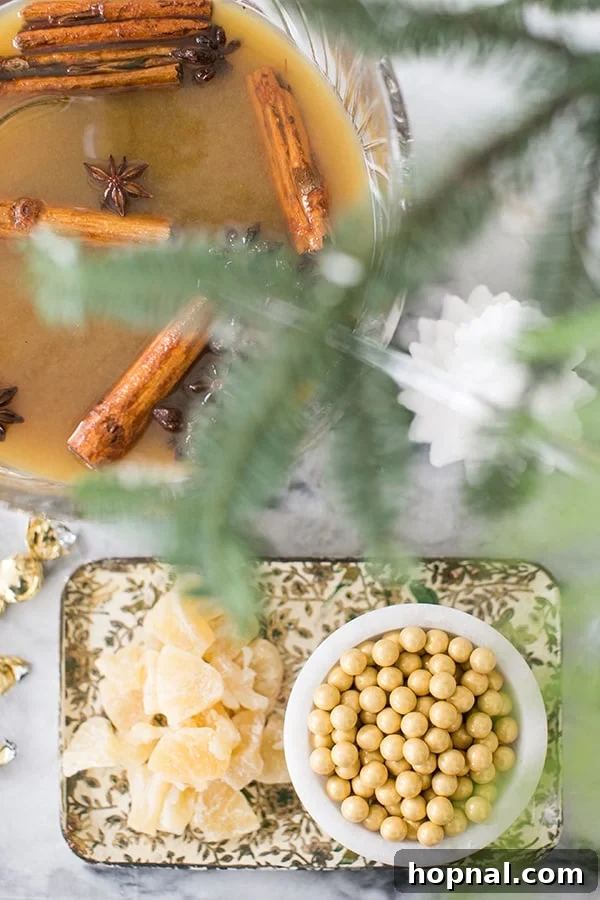 Overhead view of a festive holiday drink station featuring a punch bowl filled with mulled cider, surrounded by elegant decor and garnishes