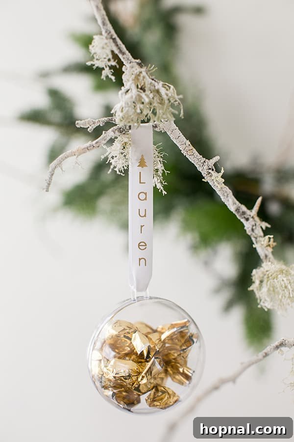 A delicate clear bauble ornament, filled with shiny gold candies, hanging as a personalized festive party favor or decor