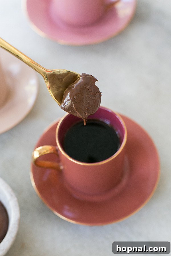 Hazelnut Cocoa Indulgence 4 A golden spoon laden with a generous dollop of rich chocolate hazelnut spread gracefully descends into a steaming cup of freshly brewed hazelnut coffee, symbolizing the blissful fusion of flavors.