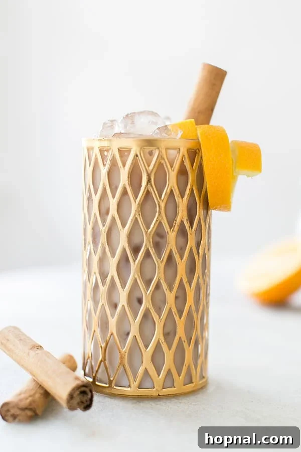 Cold brew coffee recipe in a cold glass with an orange rind and cinnamon stick 
