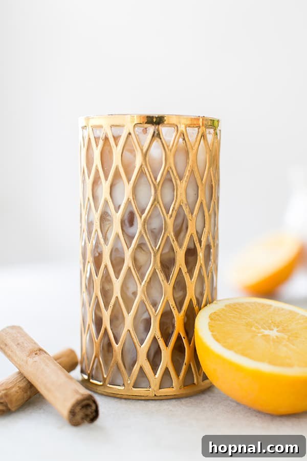 Cold brew coffee in a gold glass with cream and cinnamon.