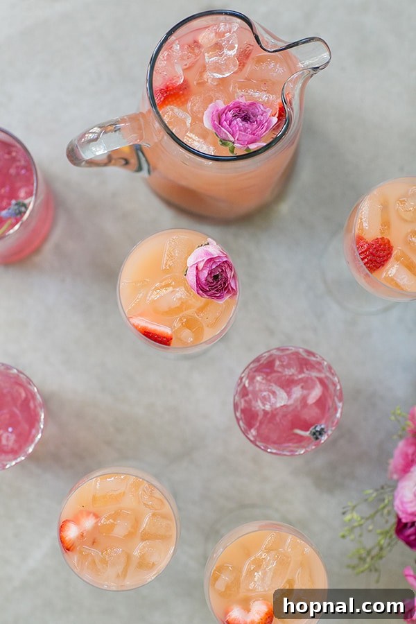 A refreshing rosé spritzer, beautifully garnished with edible flowers, served in a pitcher, ready to be enjoyed at a Valentine's Day party.