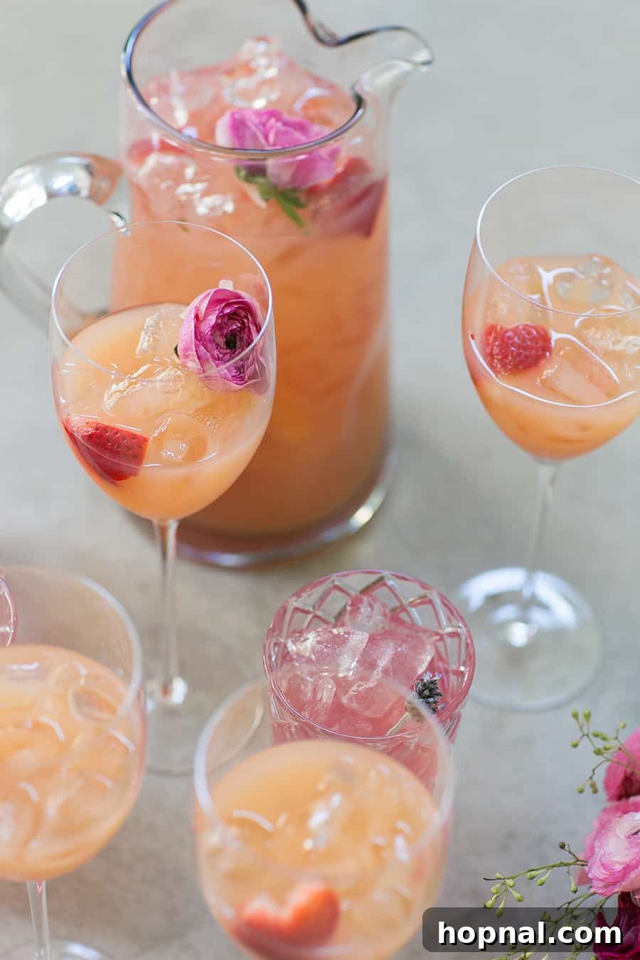 A pitcher of refreshing rosé spritzer, elegantly presented with a garnish of edible flowers, perfect for a special occasion.