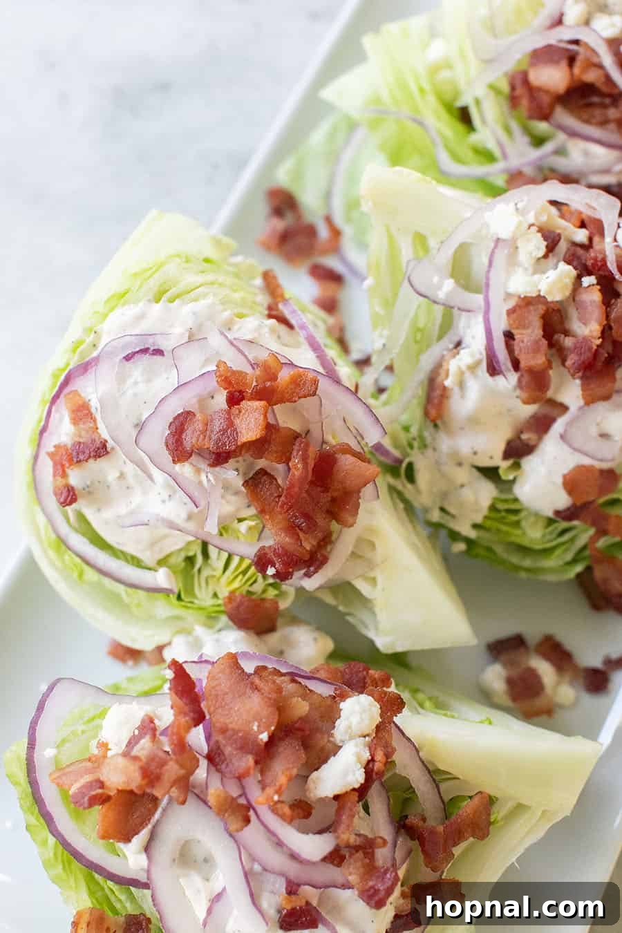 A refreshing wedge salad with crispy bacon, red onions, and a creamy dressing, ideal for balancing heavier game day fare.