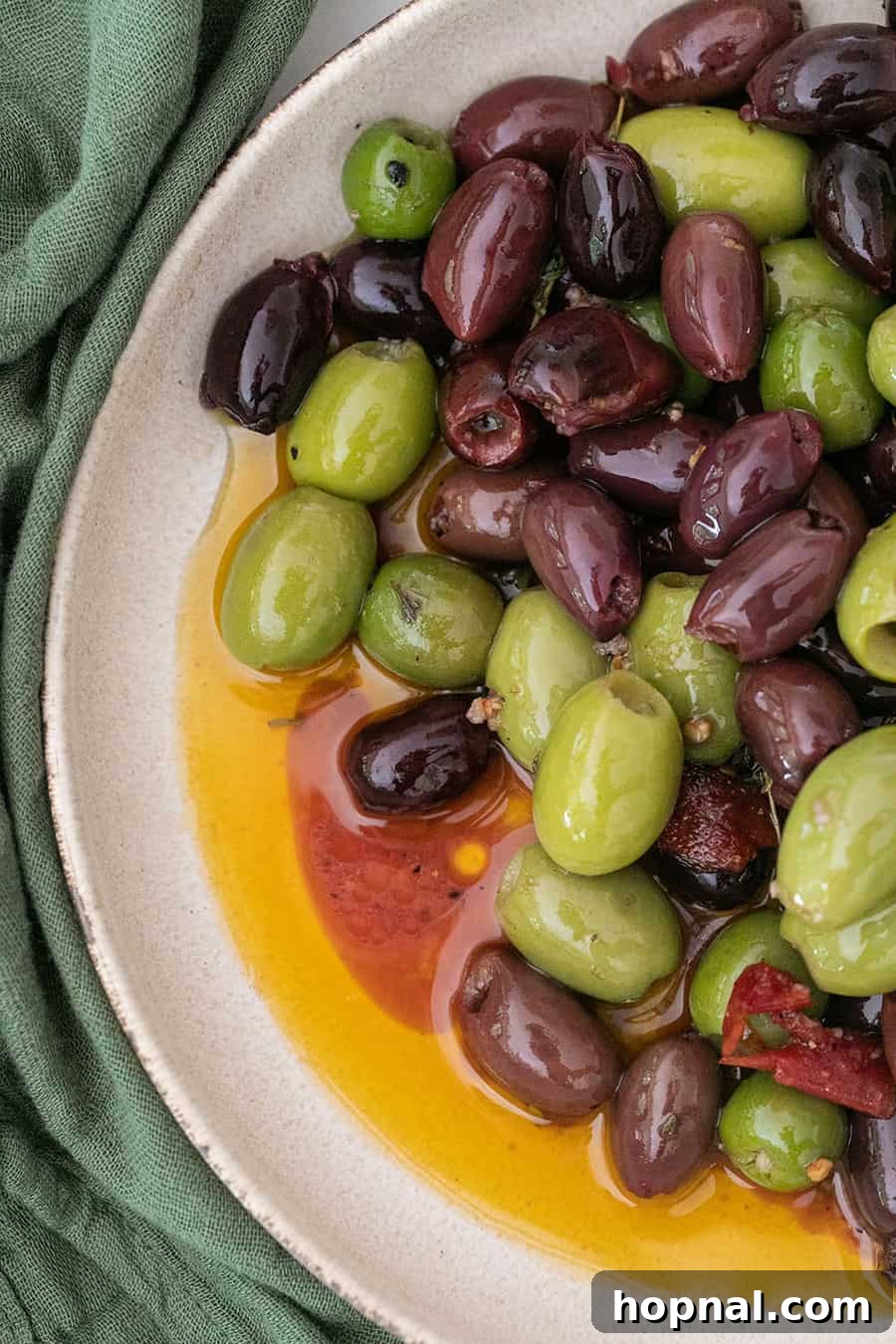 A bowl of warm marinated olives, infused with herbs and spices, a simple yet elegant appetizer.