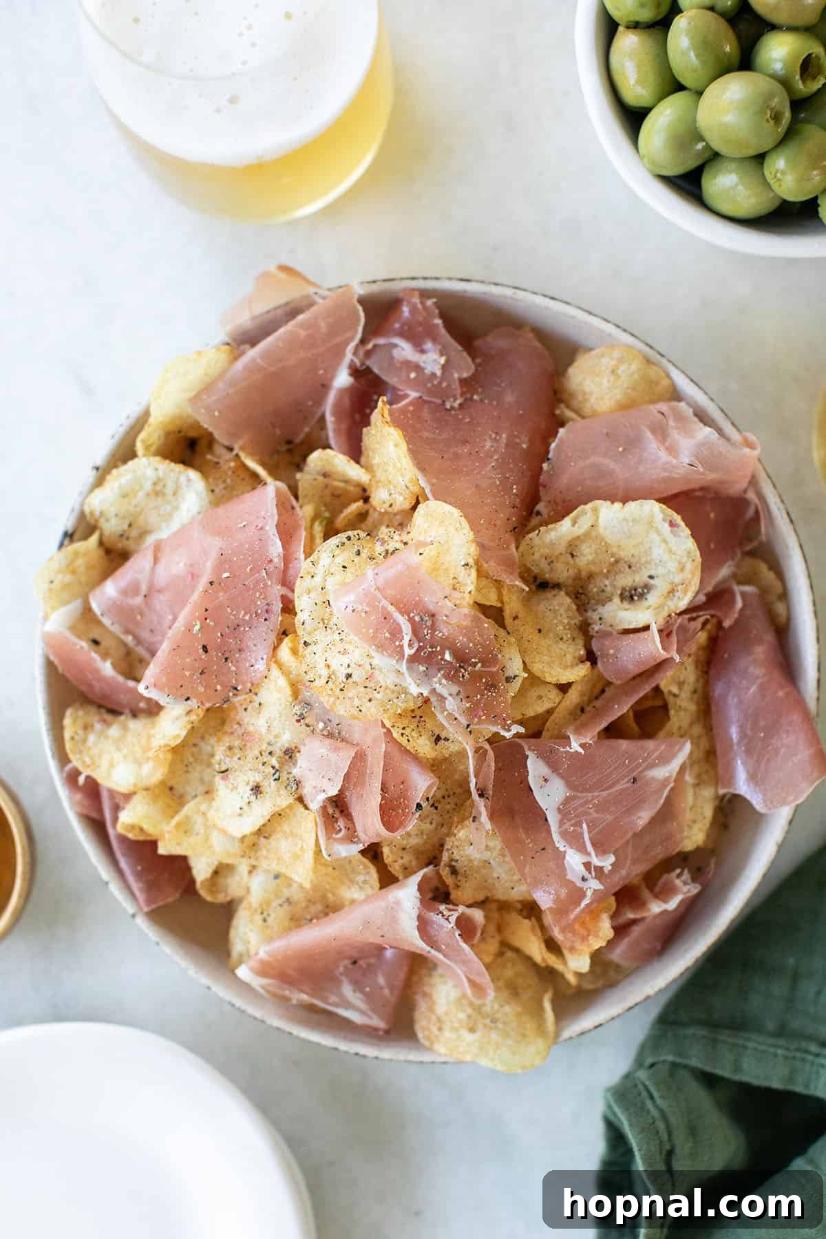 Gourmet truffle potato chips elegantly served with slices of prosciutto for a sophisticated game day snack.