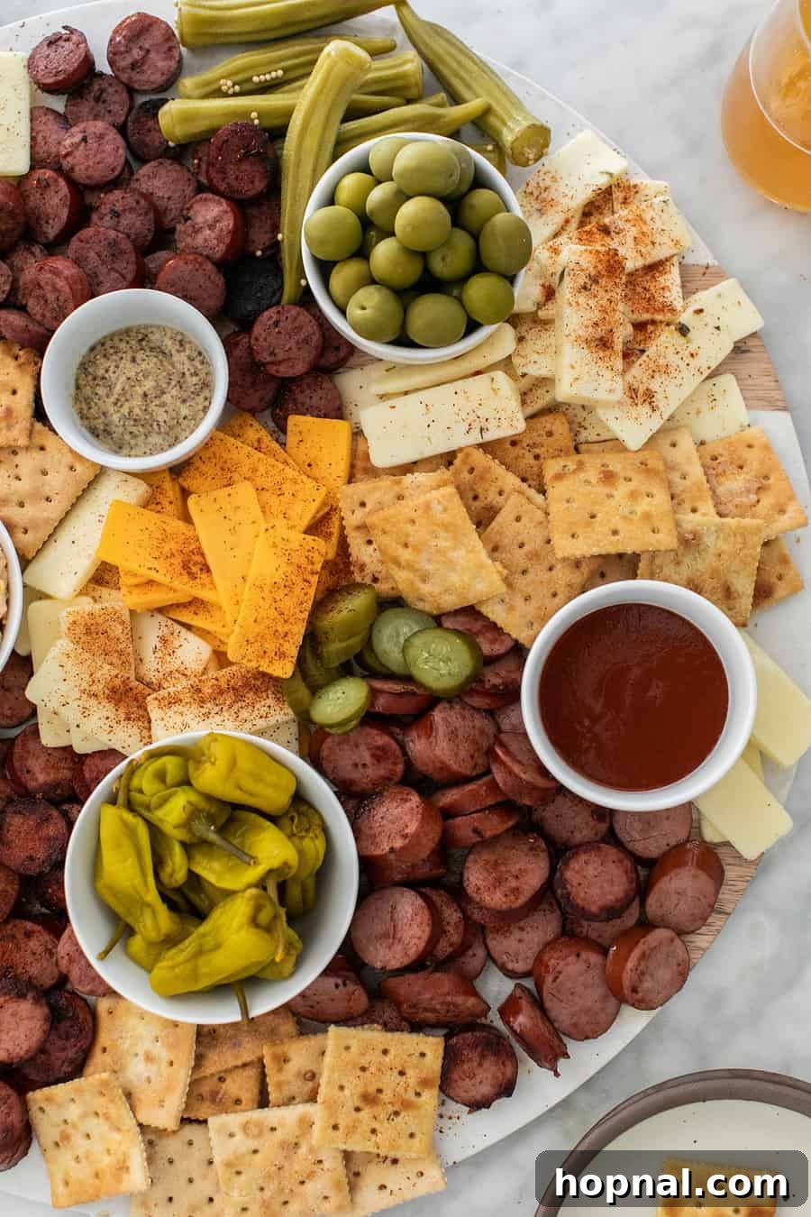 A rustic southern-inspired charcuterie board overflowing with grilled sausage, various cheeses, and pickled vegetables.