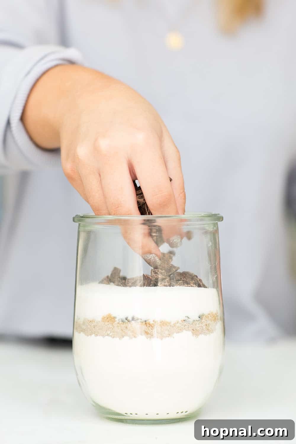 Topping off the cookie mix jar with generous chunks of dark chocolate, forming the final layer.