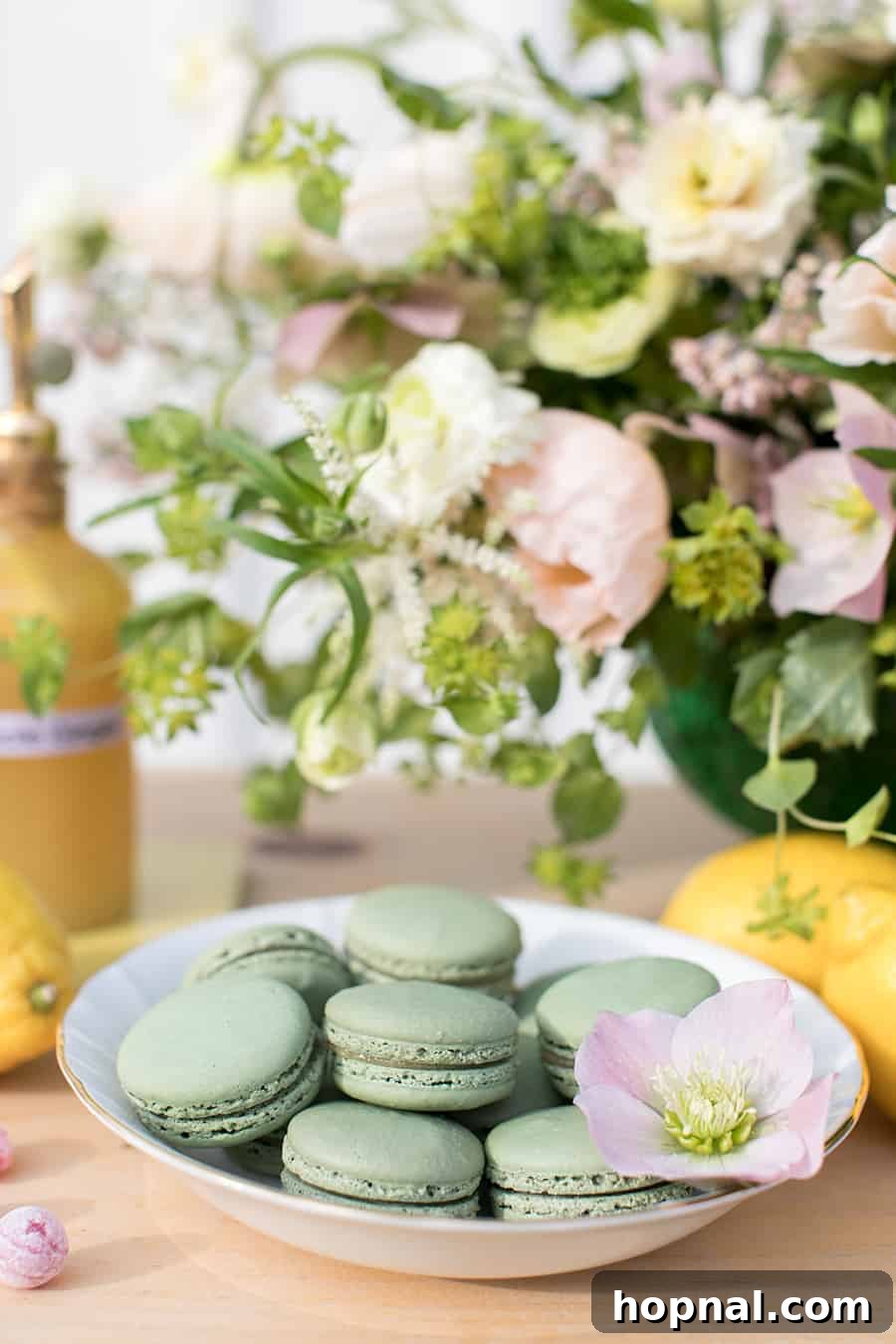 A pristine white bowl filled with an assortment of vibrant green macarons, adding a pop of color and French elegance to the dessert display.