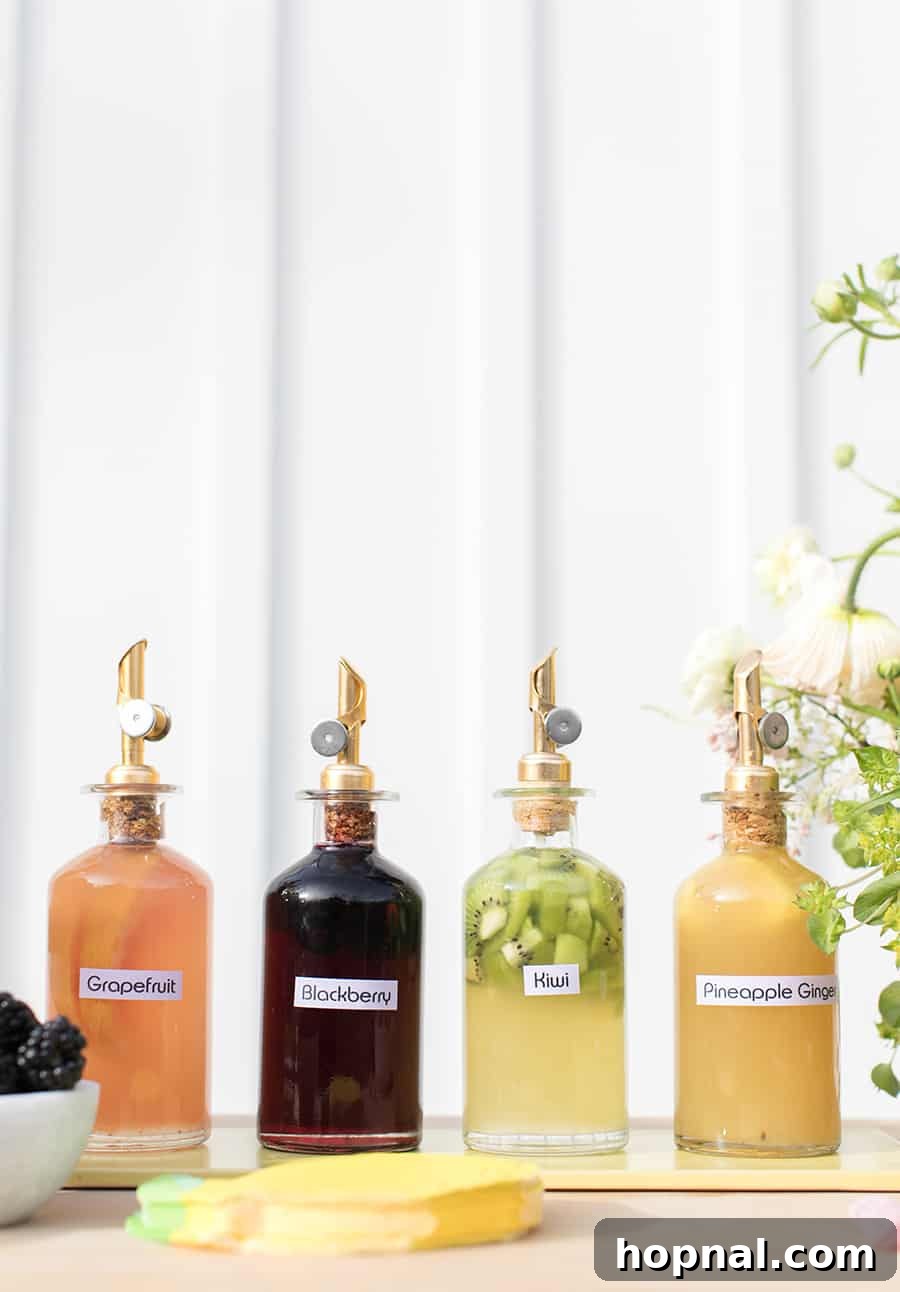 Close-up of vibrant homemade syrups, including kiwi, grapefruit, and pineapple ginger, displayed in stylish glass bottles with labels.