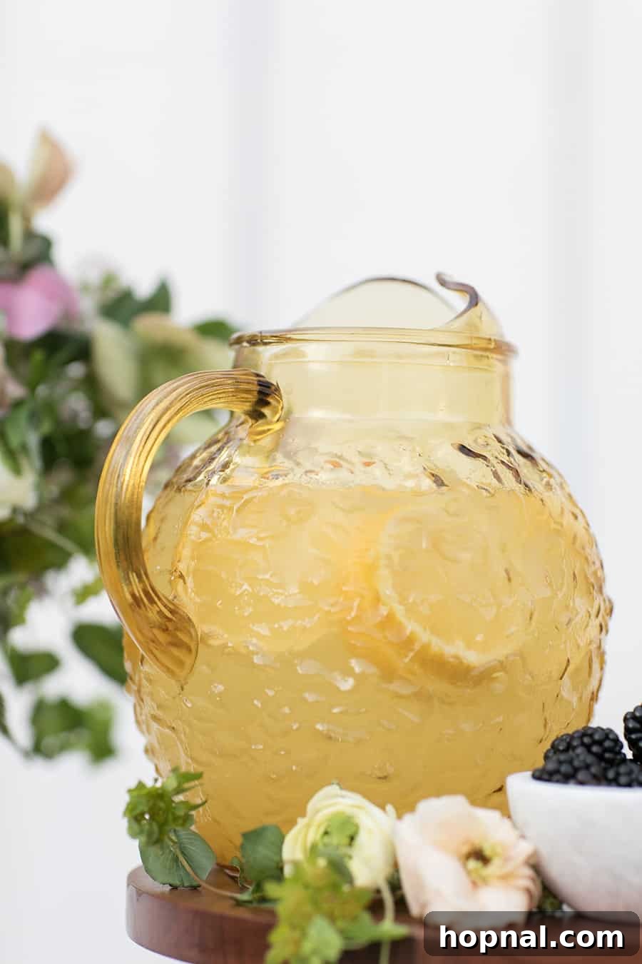 A large, sunny yellow pitcher brimming with freshly made lemonade, garnished with vibrant lemon slices, poised for serving.