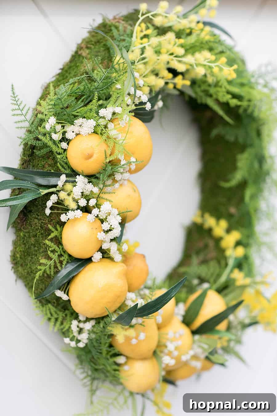 A beautifully crafted wreath adorned with vibrant faux lemons and lush green leaves, adding a festive and natural touch to the stand.