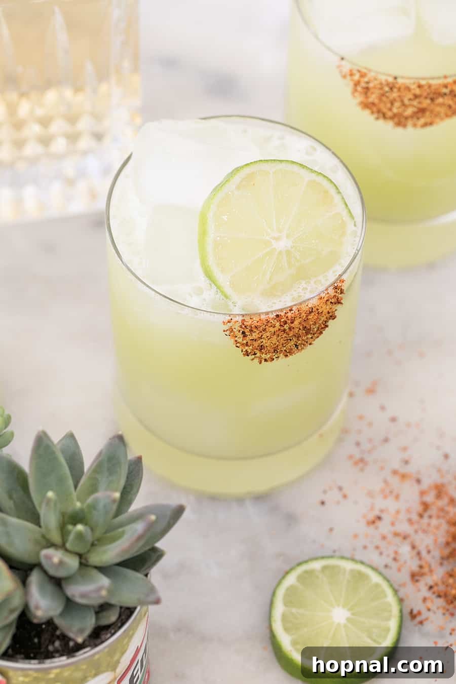 Close-up of a honeydew margarita with a lime slice garnish and chili salt rim, highlighting its refreshing appeal.