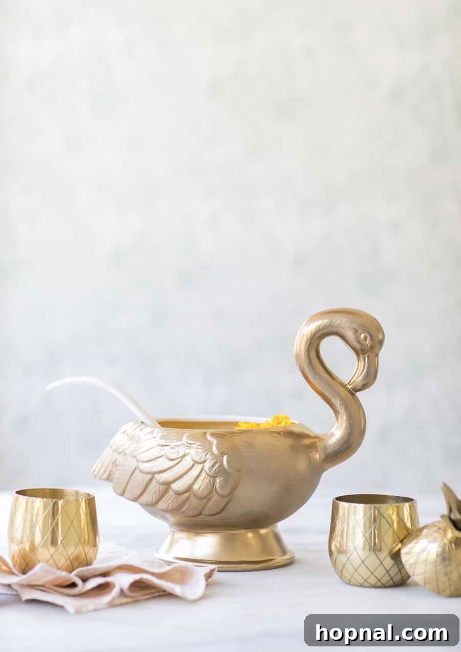 Vibrant tropical punch served in an elegant golden swan punch bowl, adorned with fresh fruit slices and ice