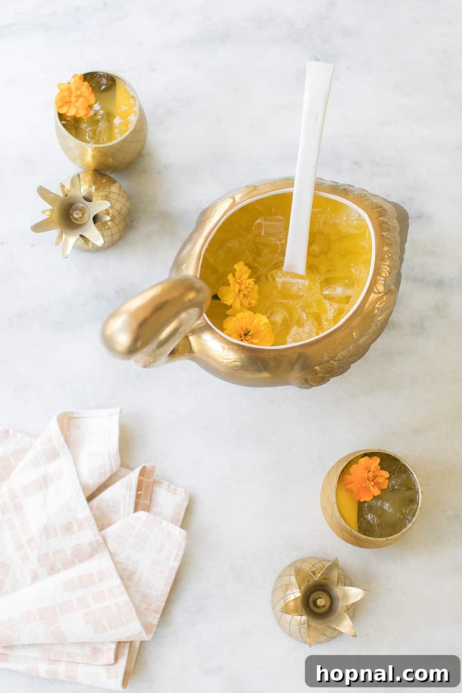 Close-up view of the golden tropical punch being ladled from the decorative bowl, showing vibrant color and ice