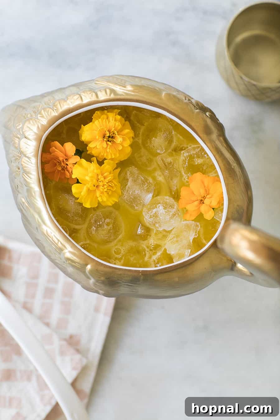 Overhead shot of a large, beautiful punch bowl filled with the glowing Sunset Swan tropical cocktail, surrounded by a festive setting